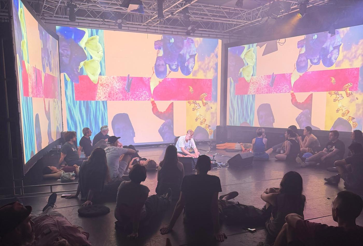 Audience members sit and lie on the floor surrounded by immersive projection screens at Alone Together in London