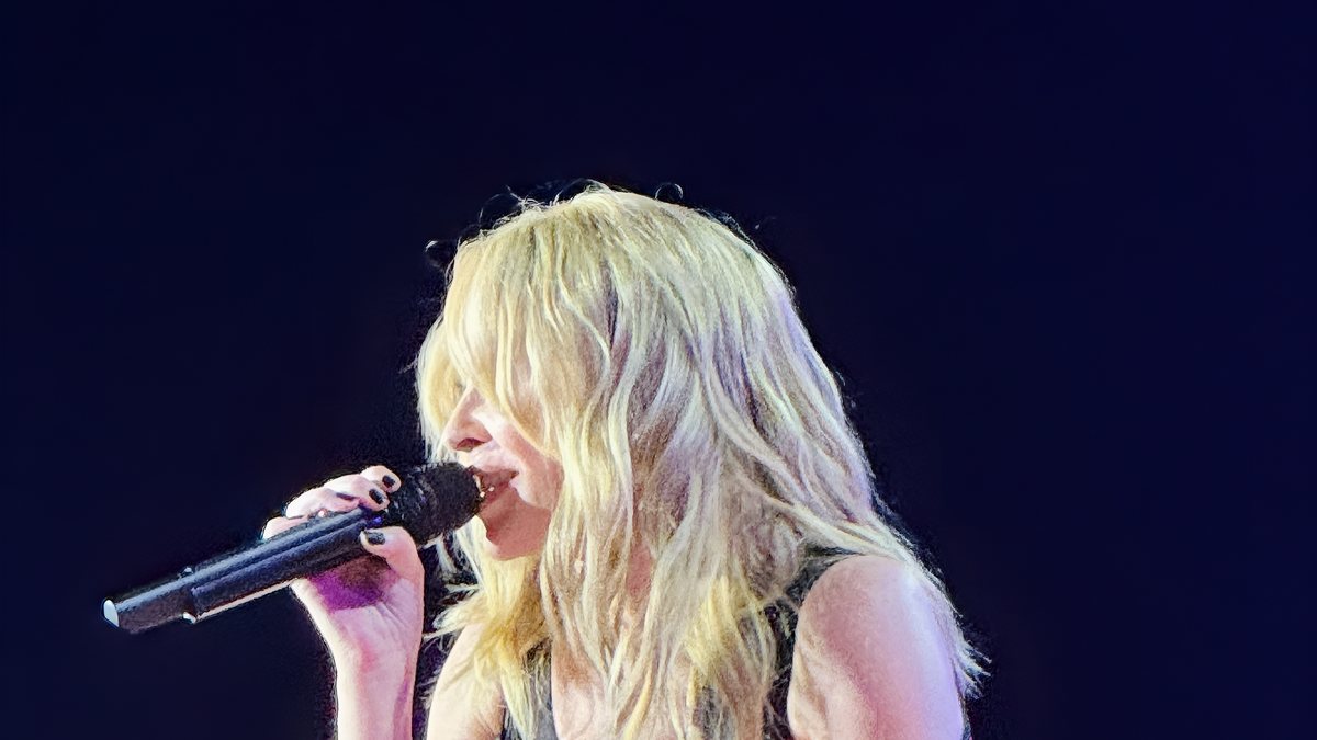Australian pop artist Kylie Minogue singing into a microphone during a live performance