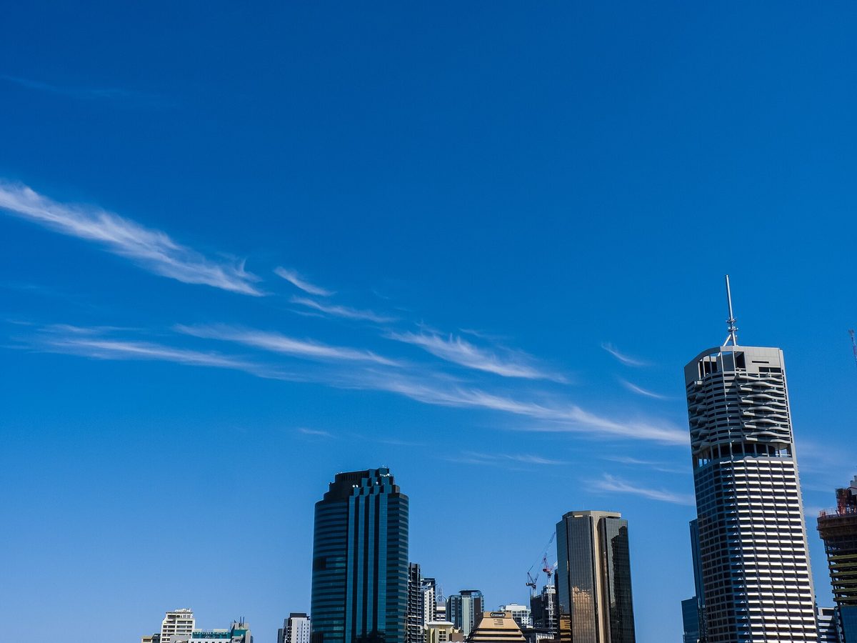 Brisbane office towers rising against a blue sky streaked with high cirrus cloud, seen from the Story Bridge.