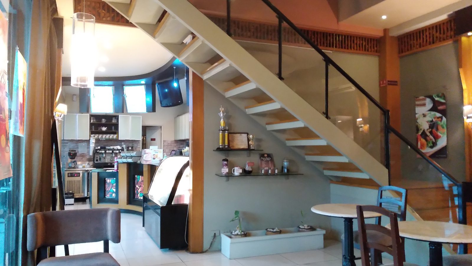 Café interior with armchairs, marble tables and a counter, the kind of room where background music plays all day