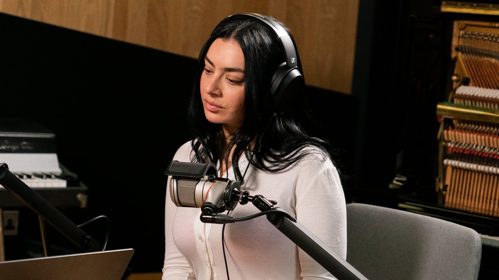 Charli xcx wearing headphones at a studio microphone during the Tape Notes podcast recording