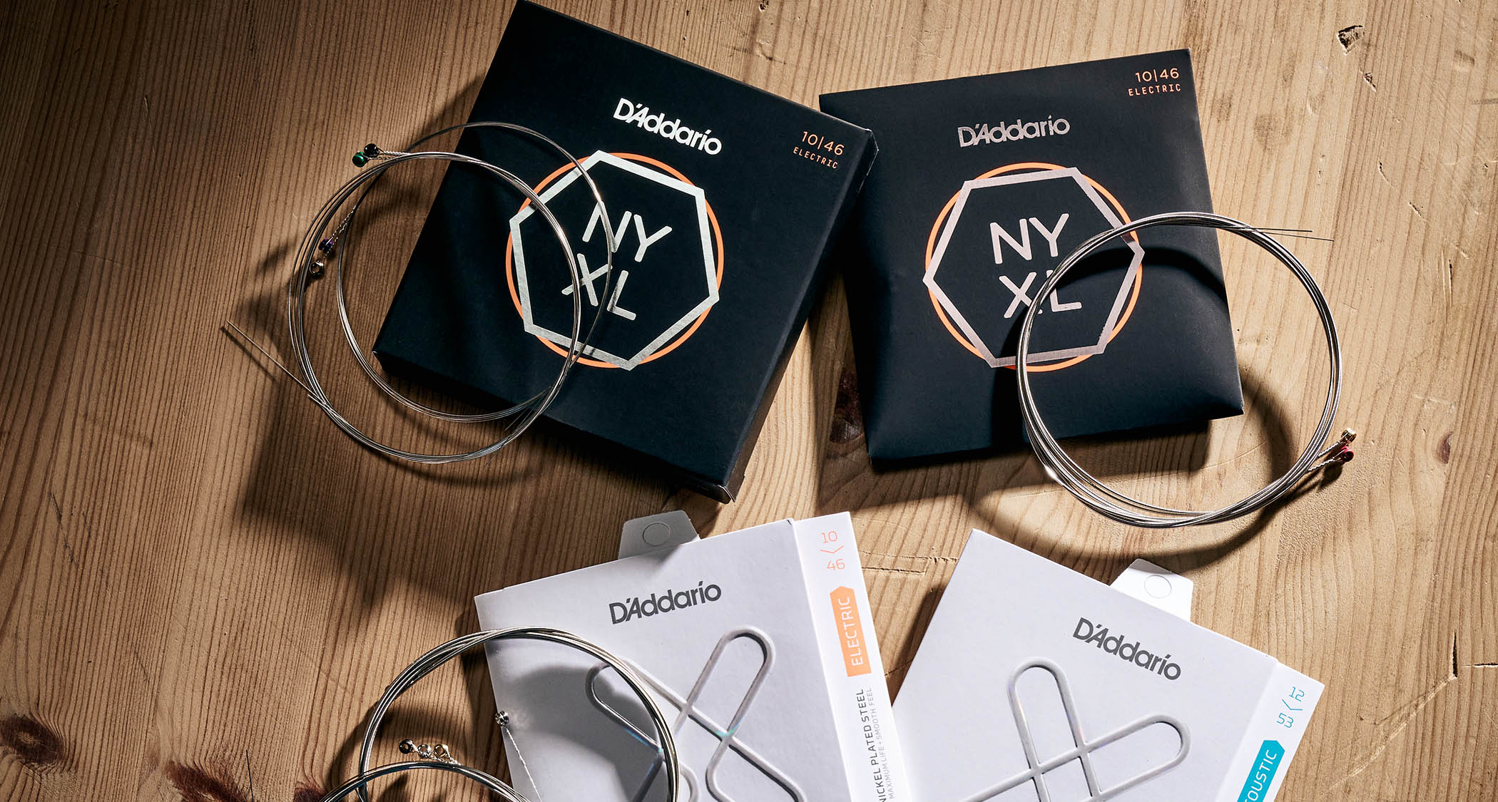 D'Addario NYXL and XT guitar string packets laid out on a wooden surface, the product line at the center of the AI music accusations