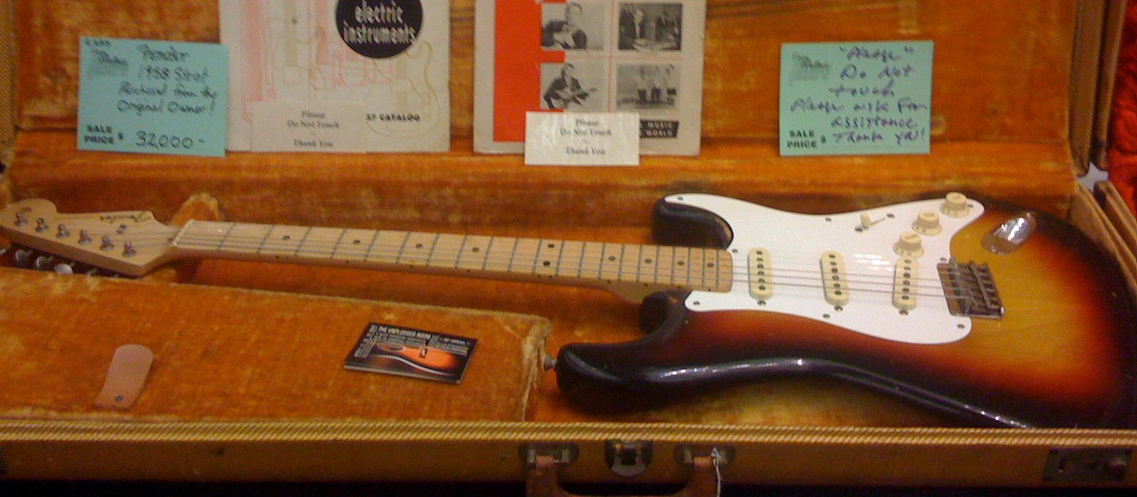 A 1958 Fender Stratocaster in its original tweed case beside vintage Fender electric instrument catalogs