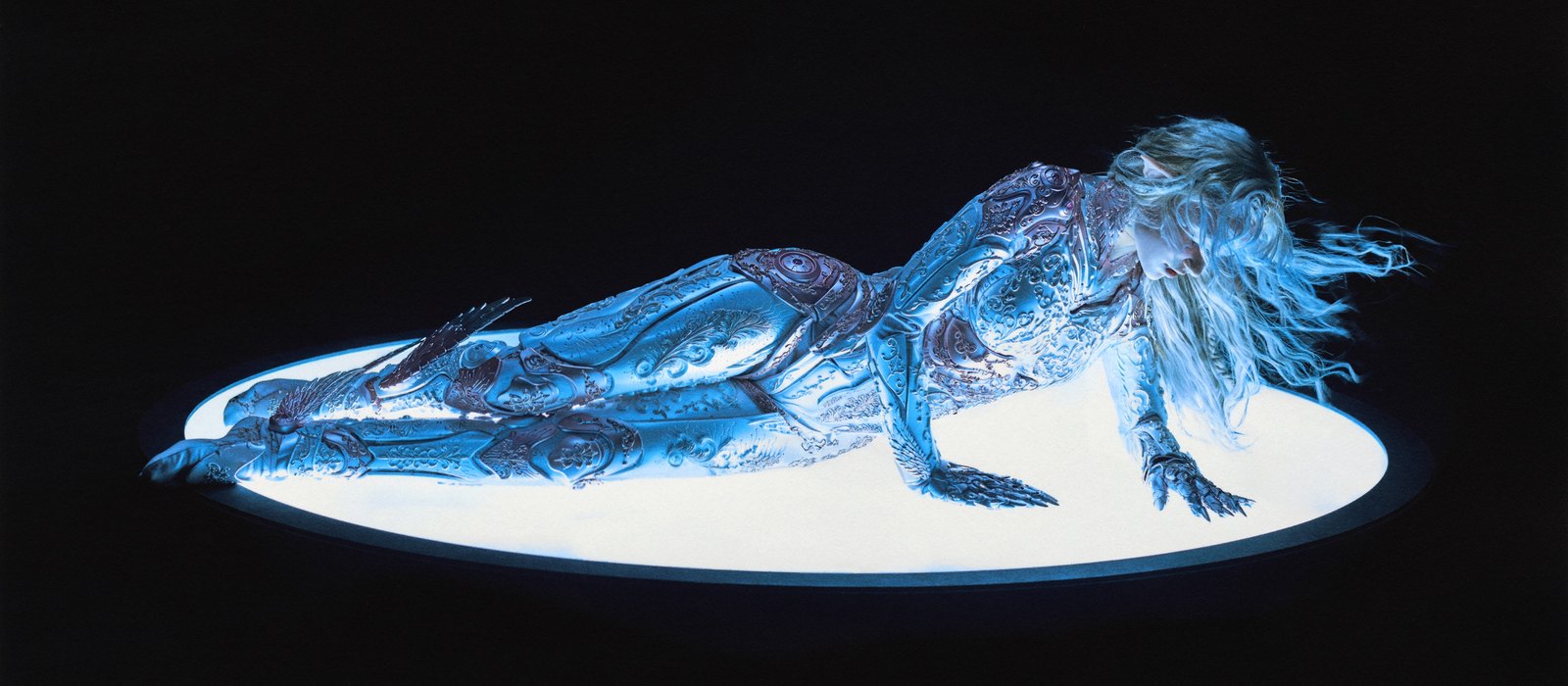 Grimes in ornate silver armour lying on a glowing white disc, the ACCELERANDO single artwork