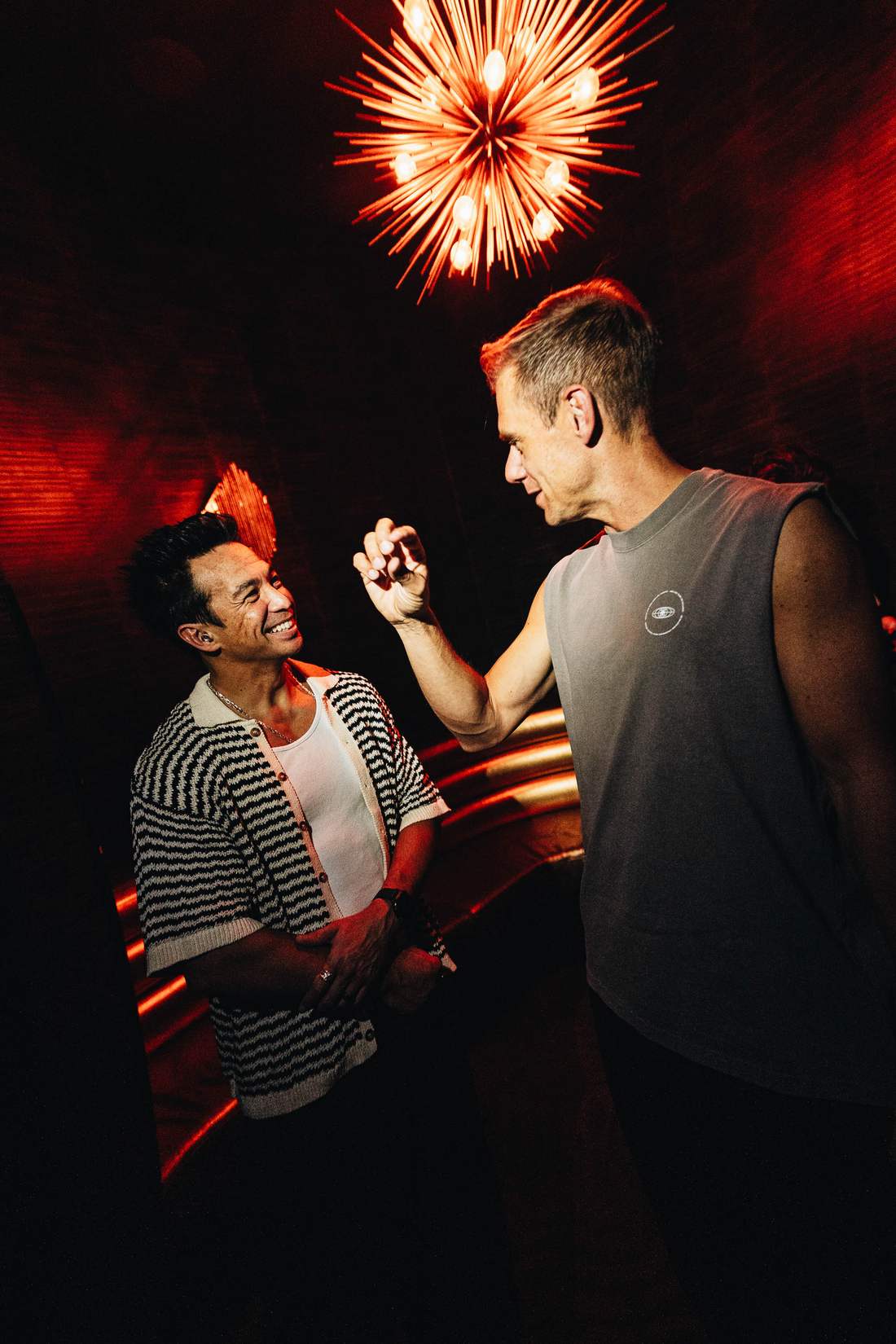 Armin van Buuren and Laidback Luke laughing together under red stage lighting
