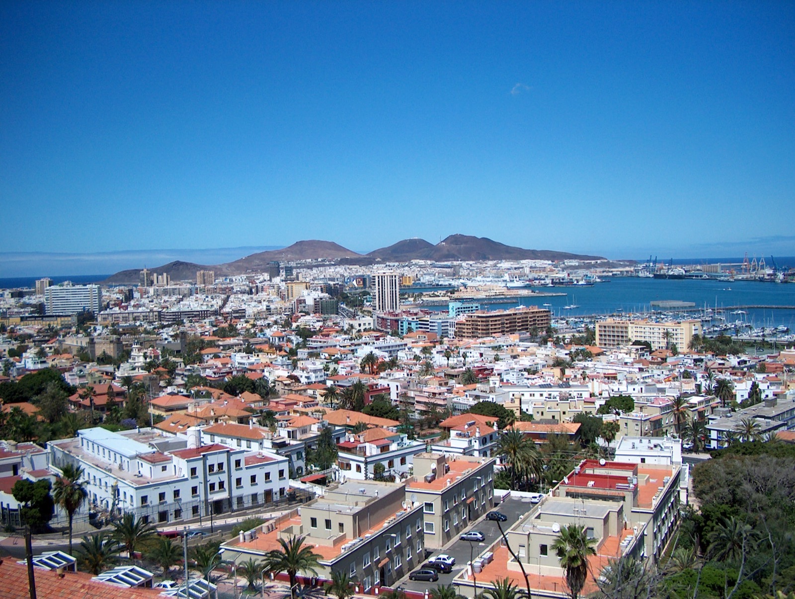 A panoramic view over the rooftops of Las Palmas de Gran Canaria towards the sea and the surrounding hills.
