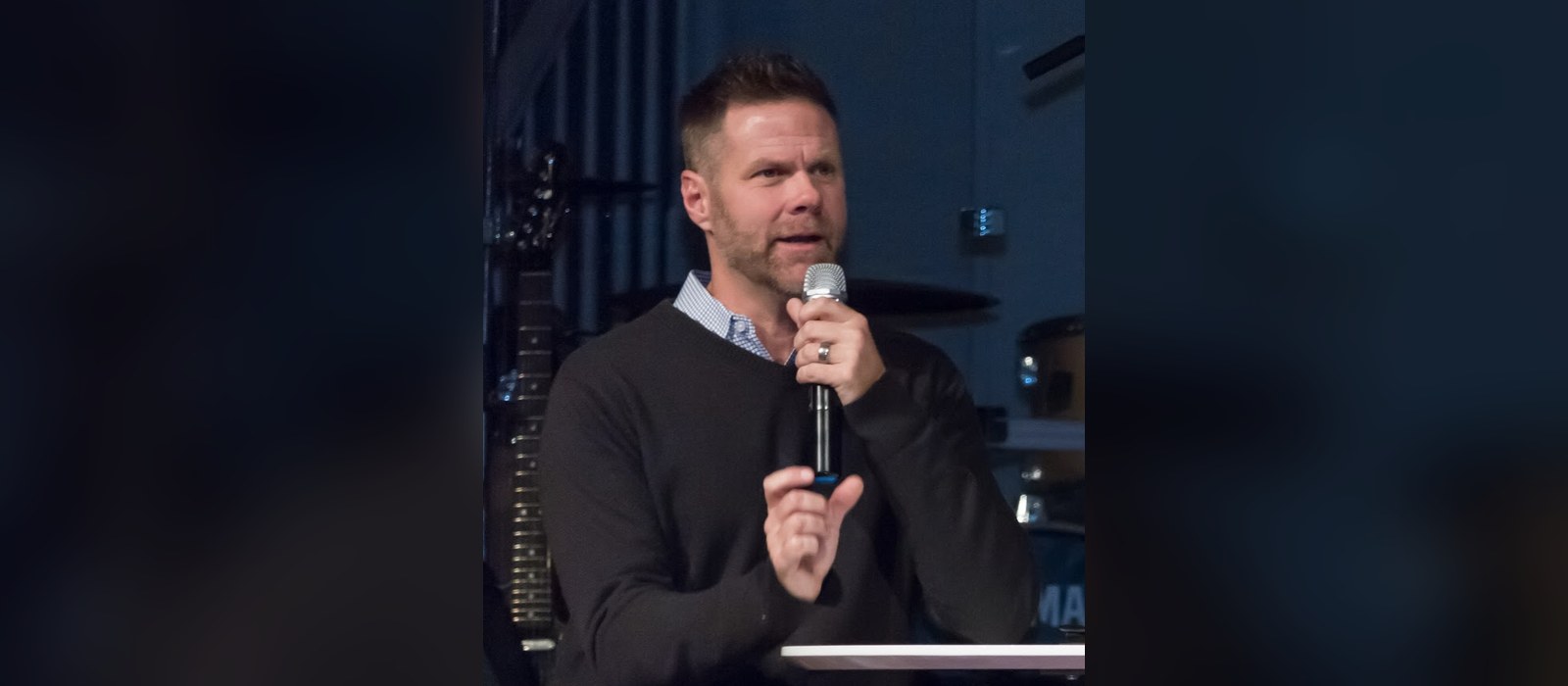 Former Audio Adrenaline singer Mark Stuart speaks into a handheld microphone at a 2016 church event