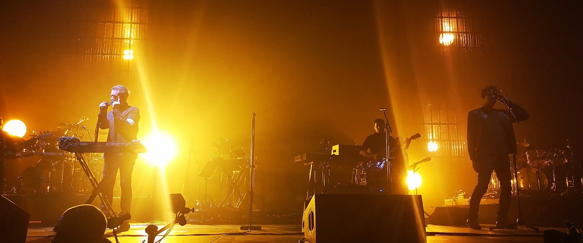 Massive Attack performing under amber stage lights at the Mediolanum Forum near Milan in 2019