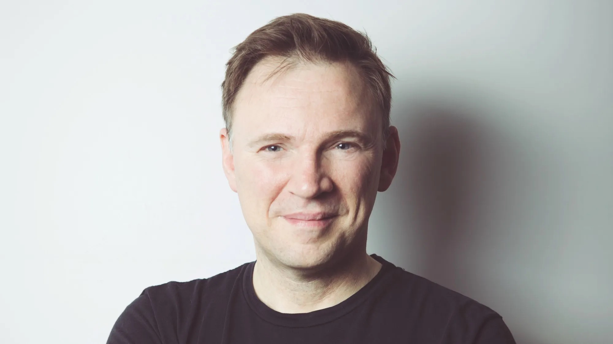 Matt Cartmell, CEO of Music Technology UK, smiling in a black t-shirt against a plain light-grey background
