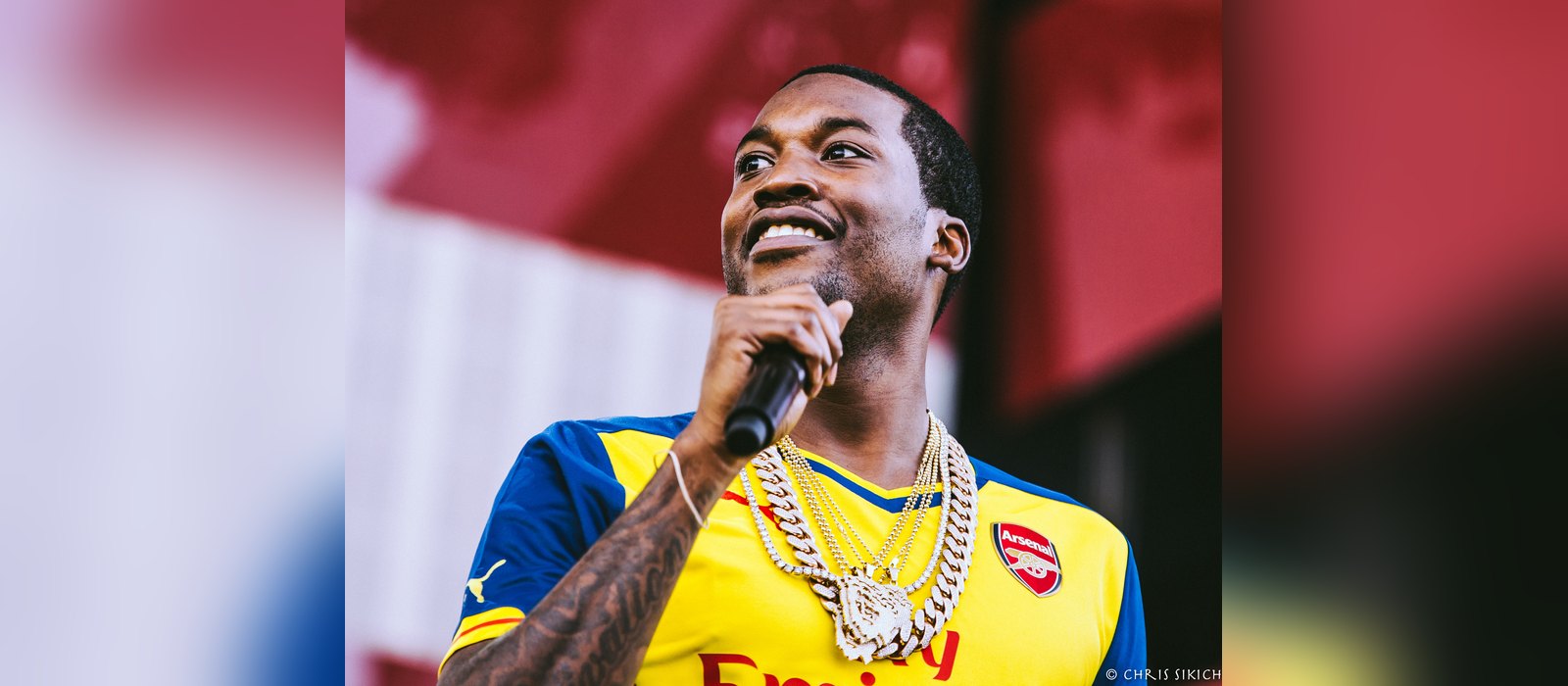 Philadelphia rapper Meek Mill smiling on stage with a microphone at Made in America 2015