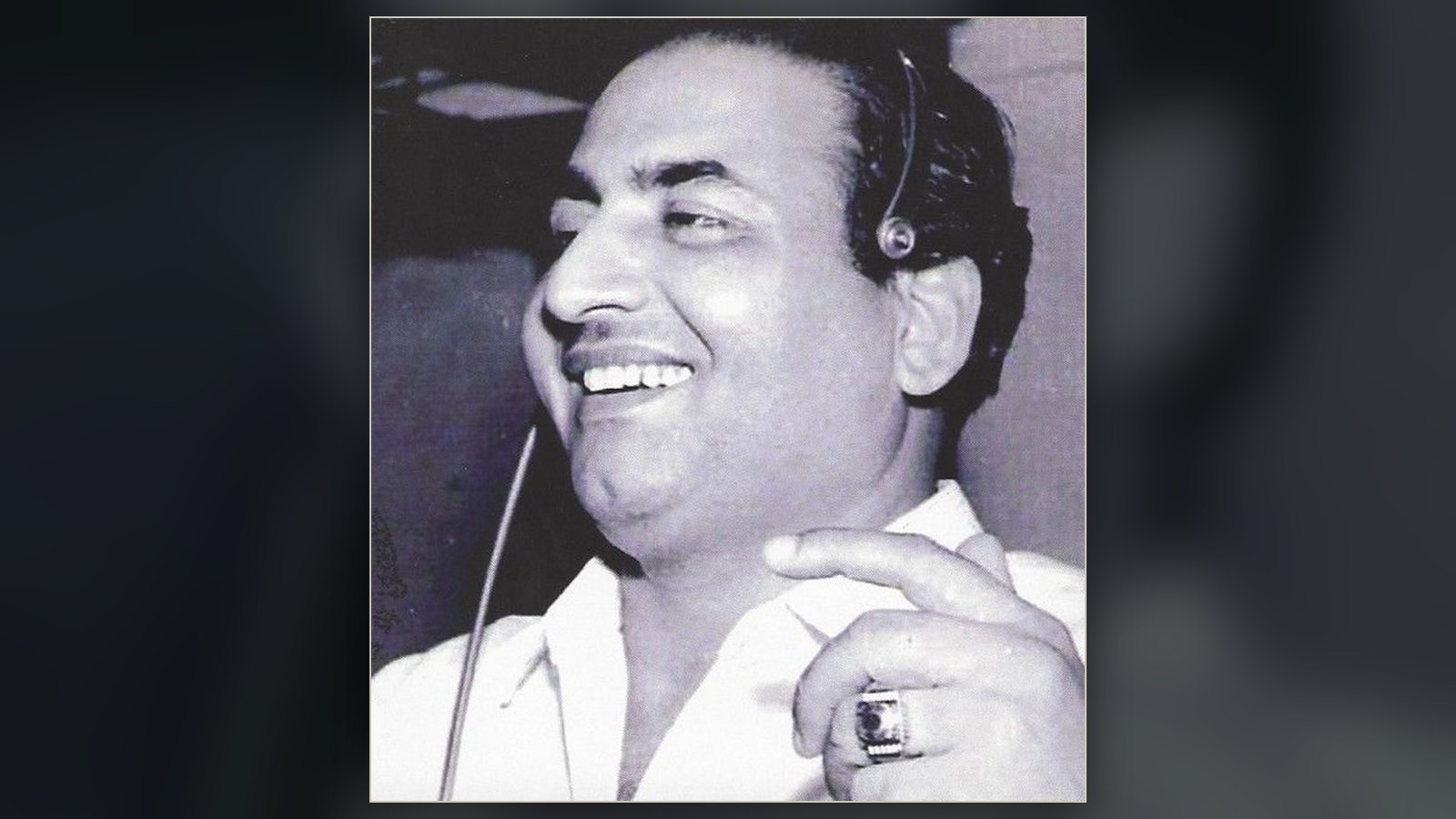 Indian playback singer Mohammed Rafi smiling at a studio microphone