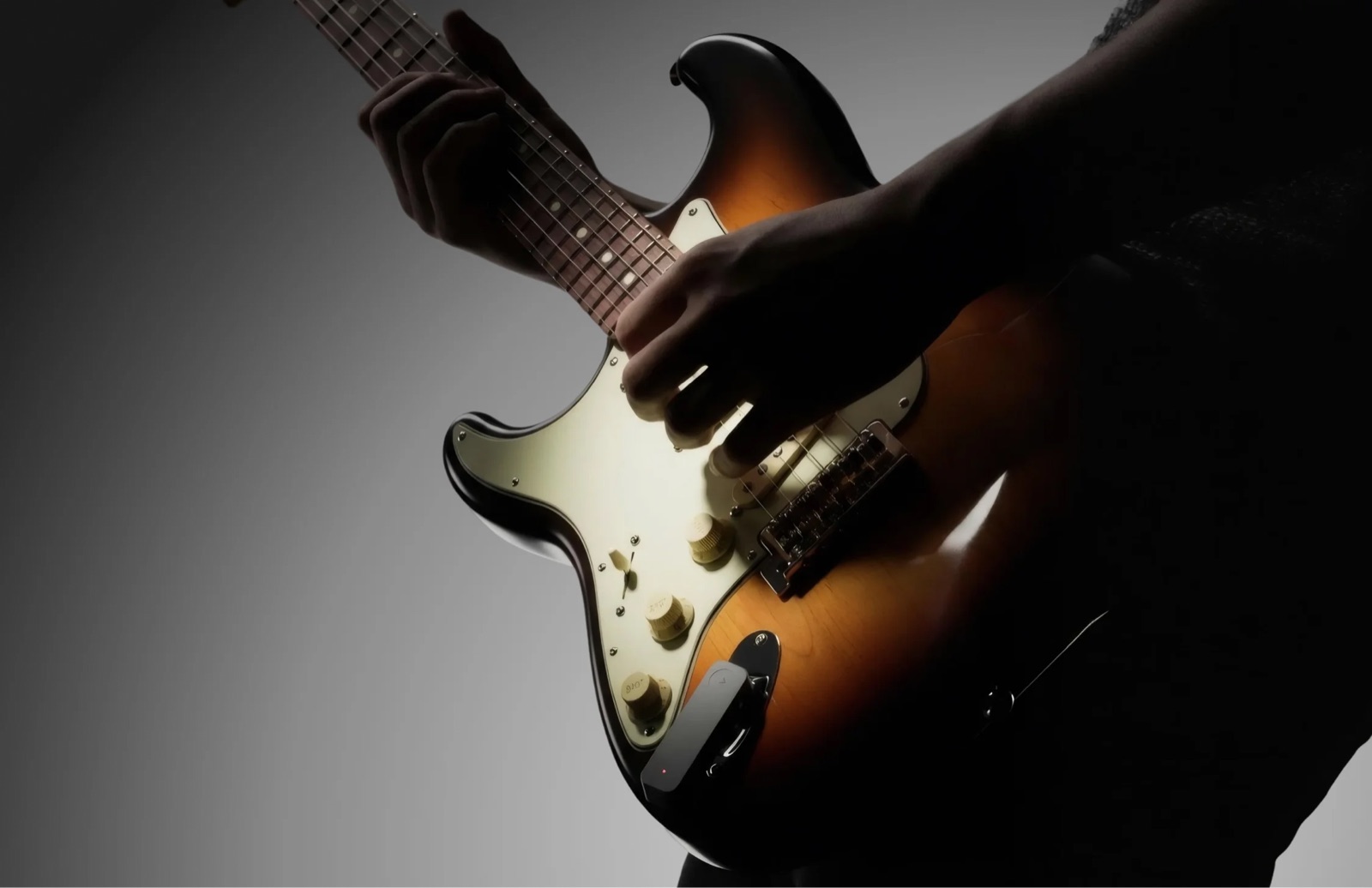 The Neko wireless device plugged into an electric guitar jack while a player performs in a dark studio