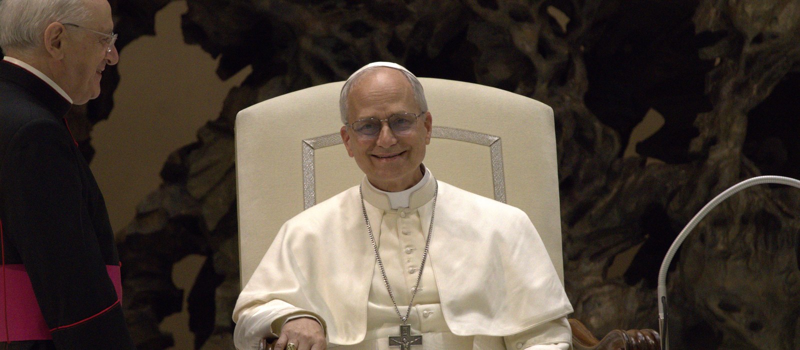 Pope Leo XIV seated and smiling in a white cassock during an audience at the Vatican