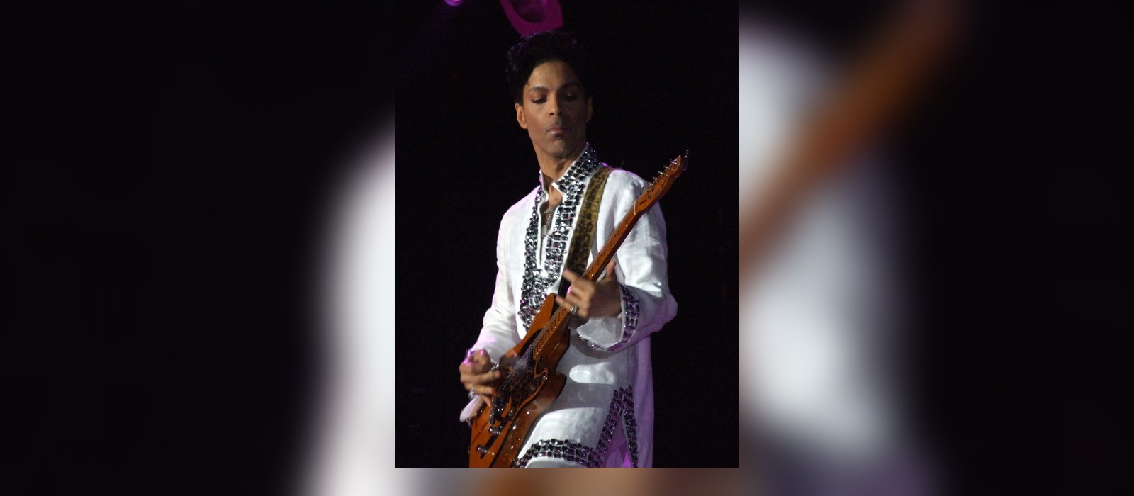 Prince performing live with a guitar, the artist whose estate denied using AI to finish the song Calabama