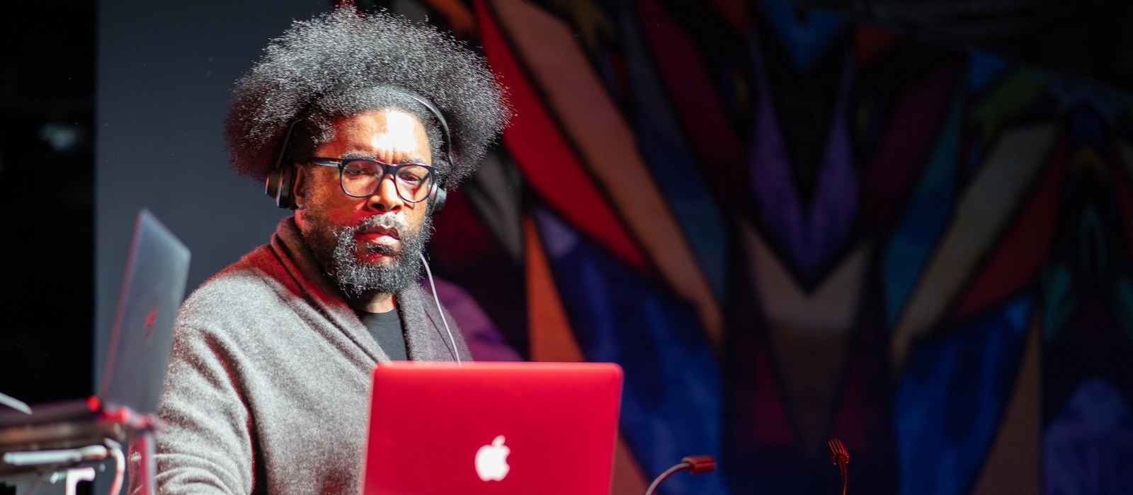 Questlove DJing with headphones on behind a red laptop at the Intel House in 2018