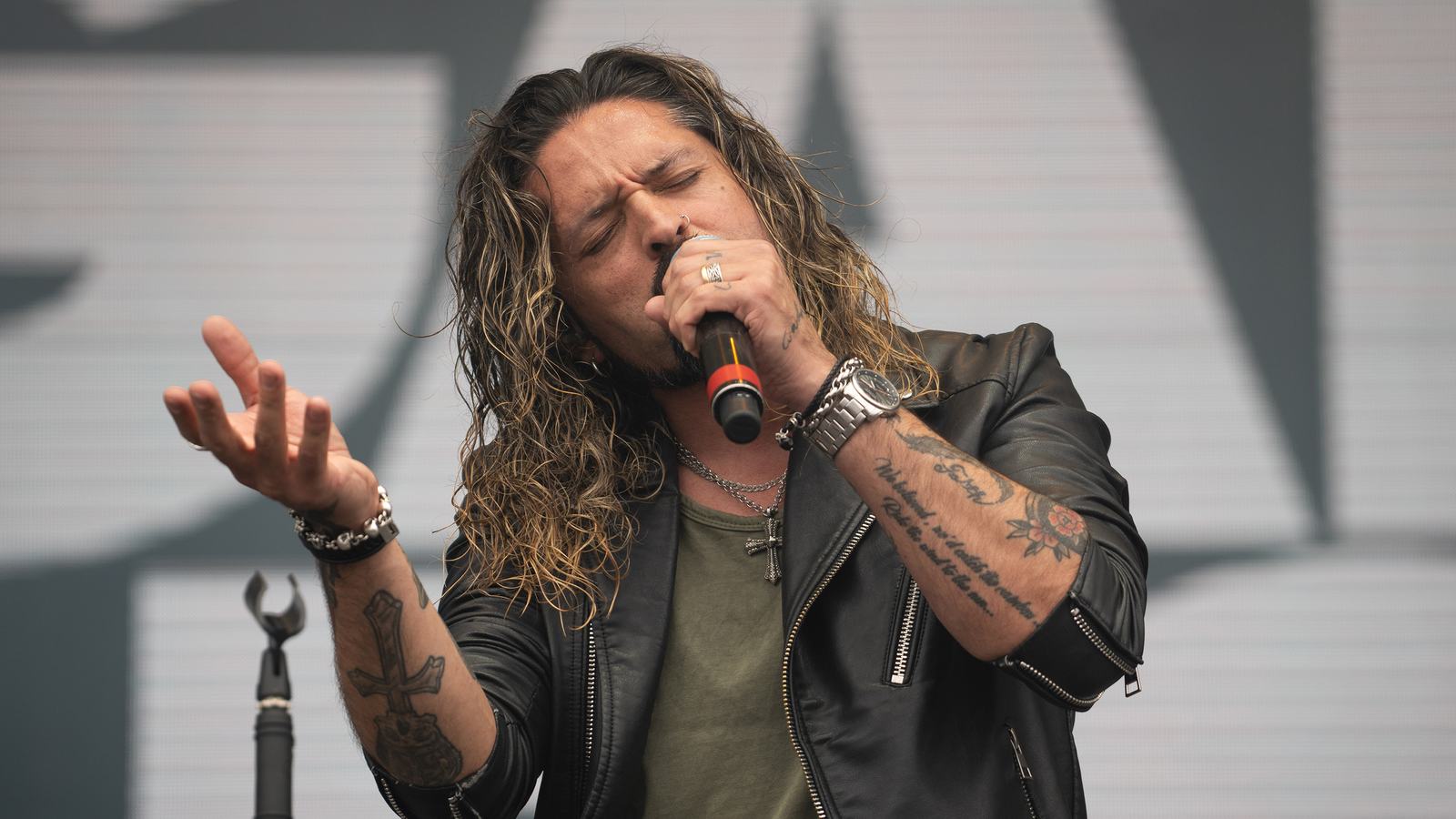 Ronnie Romero singing into a handheld mic with Elegant Weapons at Hellfest 2023 in Clisson