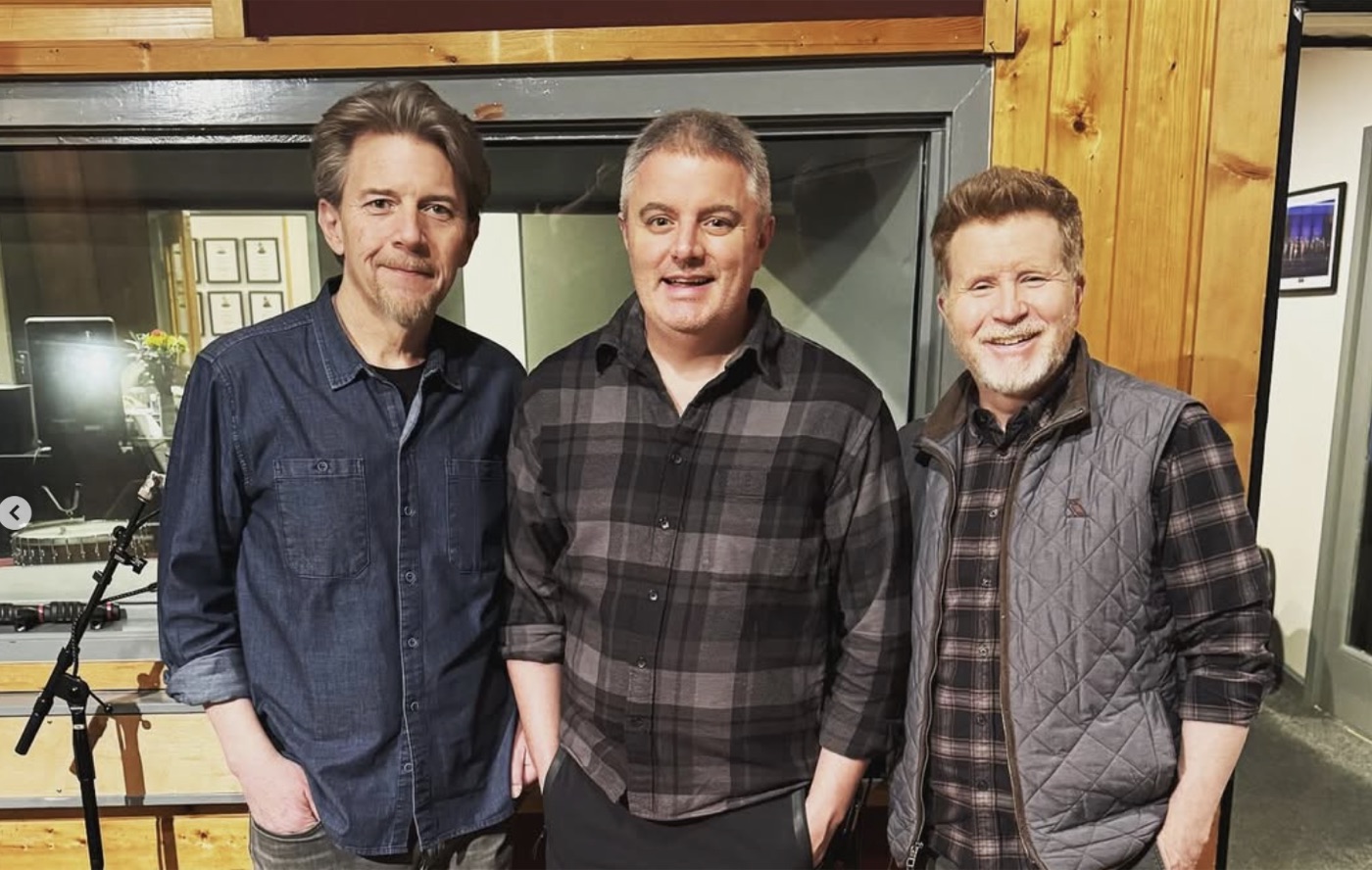 Samuel Smith stands with two fellow musicians inside a wood-paneled recording studio
