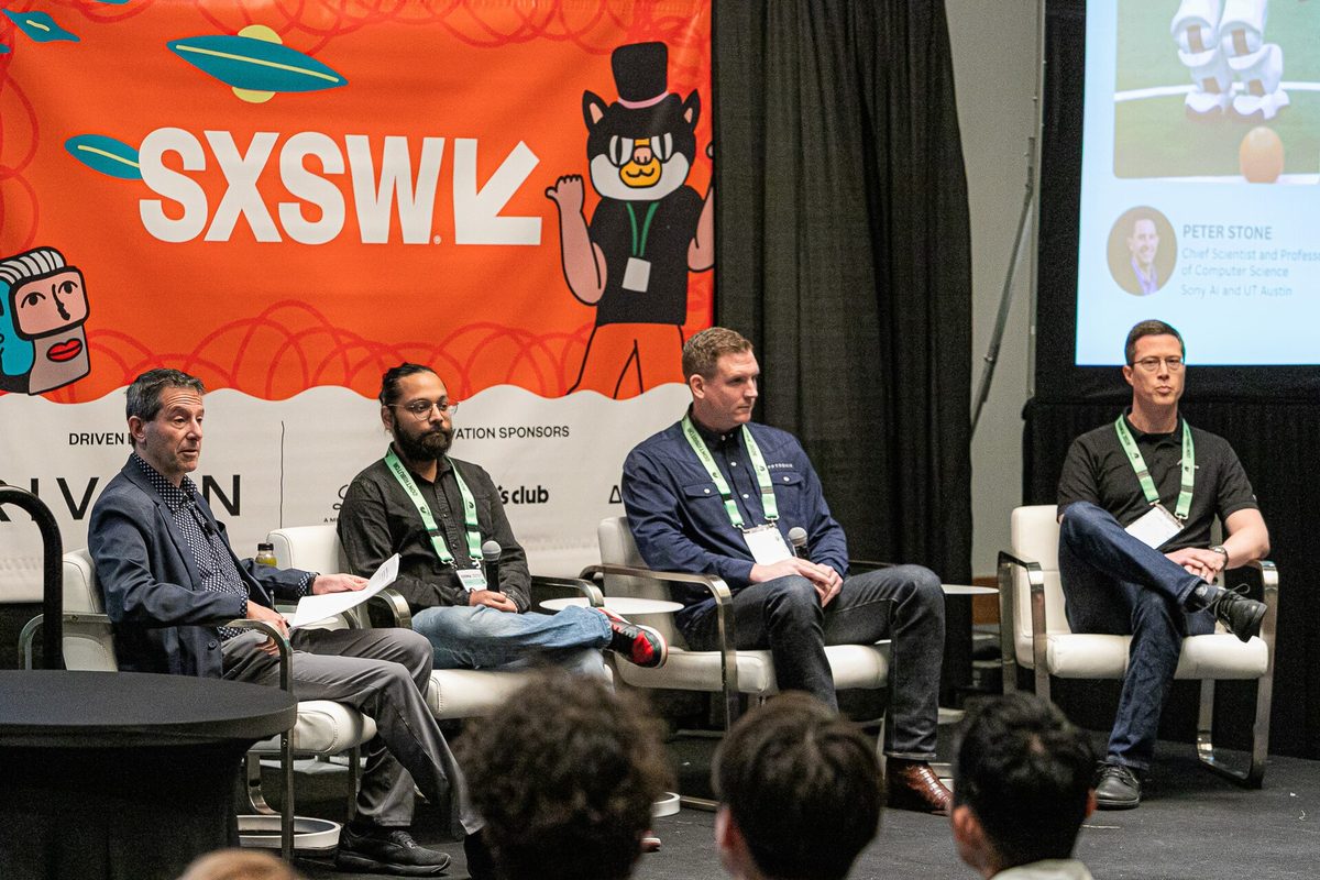 Four panellists seated in white chairs on a SXSW stage in front of an orange SXSW backdrop, with a presentation slide showing a speaker headshot beside them.