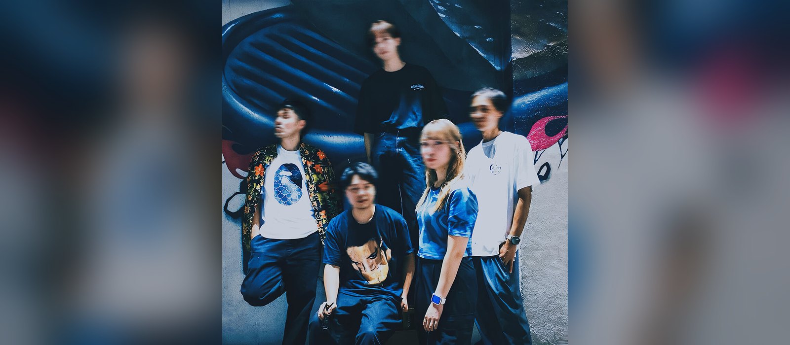 Promo photo of Japanese band THE MOTEL, the five members posed in front of a graffiti wall