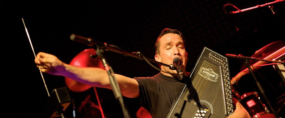 Jamie Stewart of Xiu Xiu singing and playing an autoharp on stage in Vancouver