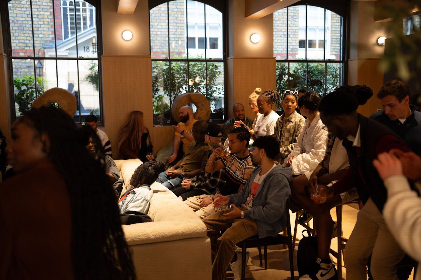 Diverse attendees gathered on couches by tall windows at the Twoshot song camp