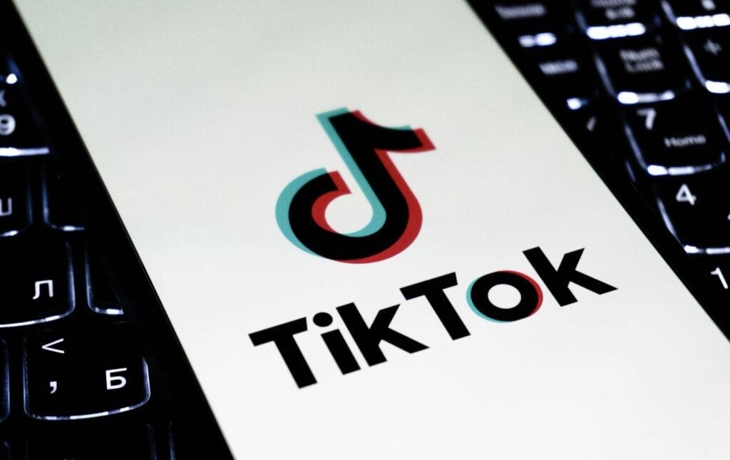 TikTok app logo displayed on a smartphone screen resting on a laptop keyboard.