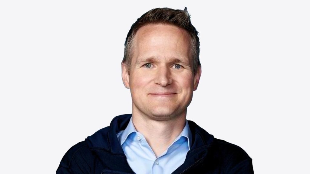 Oliver Schusser, Apple Music Vice President, wearing a dark jacket against a light grey background.